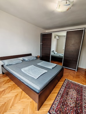 Ein modernes Schlafzimmer mit einem hölzernen Bett, einem Spiegel und einem gemusterten Teppich.