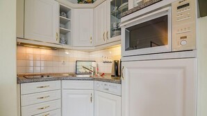 Una cucina con mobili bianchi, un forno a microonde integrato e una lavastoviglie.