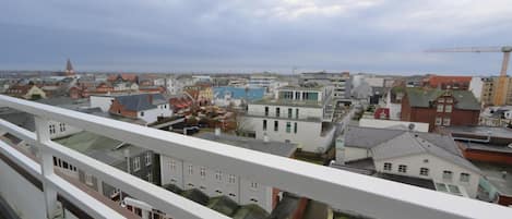 Vista desde un balcón sobre un paisaje urbano con diversos edificios, incluyendo una tienda Woolrich.