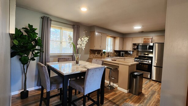 A modern kitchen with a marble countertop, stainless steel appliances, and a dining area with a table and chairs.
