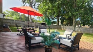 A wooden deck with outdoor furniture, including a table and chairs, and a potted plant.