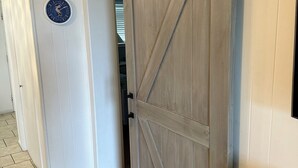 Een kamer met een schuifdeur van hout, een klok aan de muur en een betegelde vloer.