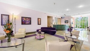A hotel lobby with a reception desk, purple and white seating, and artwork on the walls. - Right on the beach, Ocean Drive Secured Condo (Miami Beach)