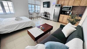 A modern apartment with a bed, sofa, coffee table, TV, kitchen area, and a dining table. - Right on the beach, Ocean Drive Secured Condo (Miami Beach)