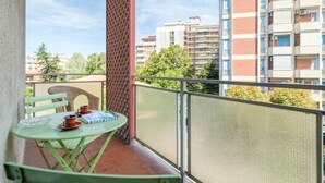 A balcony with a table and chairs, a view of buildings, and a clear sky. - Fabula Rooms - flat - 3 Suites with 3 bathrooms (Bologna)
