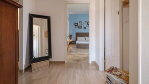 A hallway leading to a bedroom with a bed and wall-mounted pictures. - Fabula Rooms - flat - 3 Suites with 3 bathrooms (Bologna)