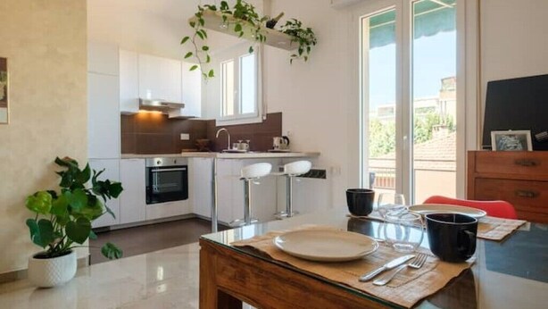 A modern kitchen with white cabinets, a built-in oven, and a bar area with stools. - Fabula Rooms - flat - 3 Suites with 3 bathrooms (Bologna)