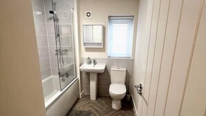 Een kleine badkamer met een douche, wastafel en toilet.