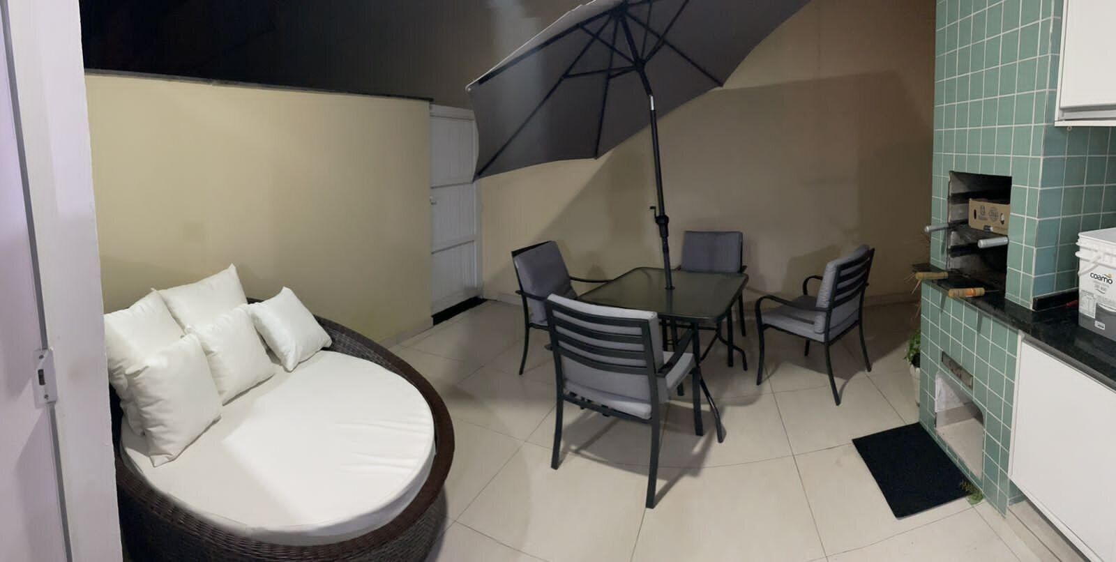 Una habitación compacta con cama redonda, una mesa de comedor con sillas, una pequeña cocina y un gran paraguas que da sombra.