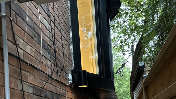 Une ruelle étroite, bordée d’un côté d’un mur de briques et de l’autre d’une clôture en bois.