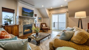 A cozy living room with a fireplace, comfortable seating, and a view of the outdoors. - The Red Barn Retreat, a reclaimed  grain barn centrally located in Kalispell MT (Kalispell)