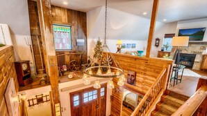 A rustic interior with wooden beams, a chandelier, a fireplace, and a Christmas tree. - The Red Barn Retreat, a reclaimed  grain barn centrally located in Kalispell MT (Kalispell)