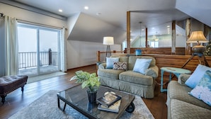 A spacious living room with a large window, a sofa set, a coffee table with a plant, and a staircase leading to an upper level. - The Red Barn Retreat, a reclaimed  grain barn centrally located in Kalispell MT (Kalispell)