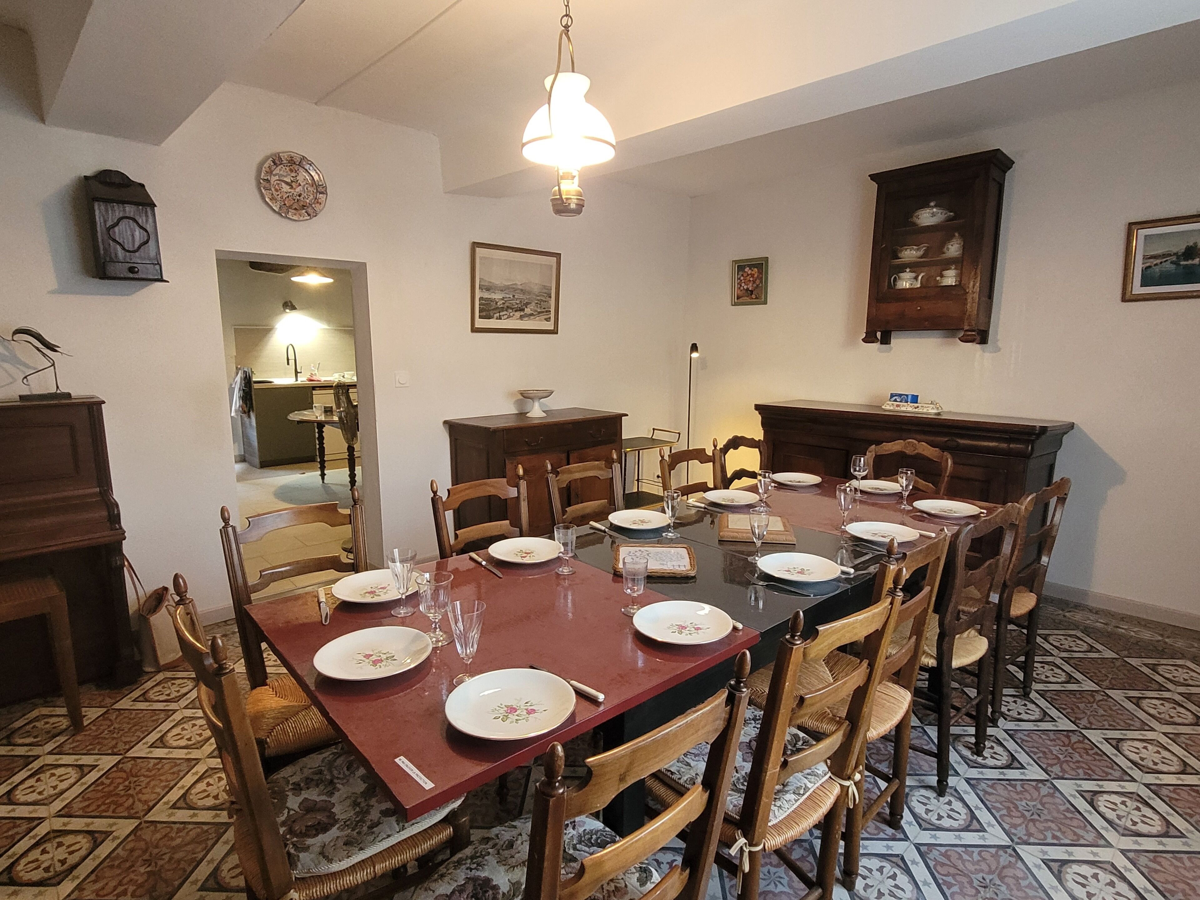 A dining room with a rectangular table set for six, surrounded by wooden chairs with woven seats.