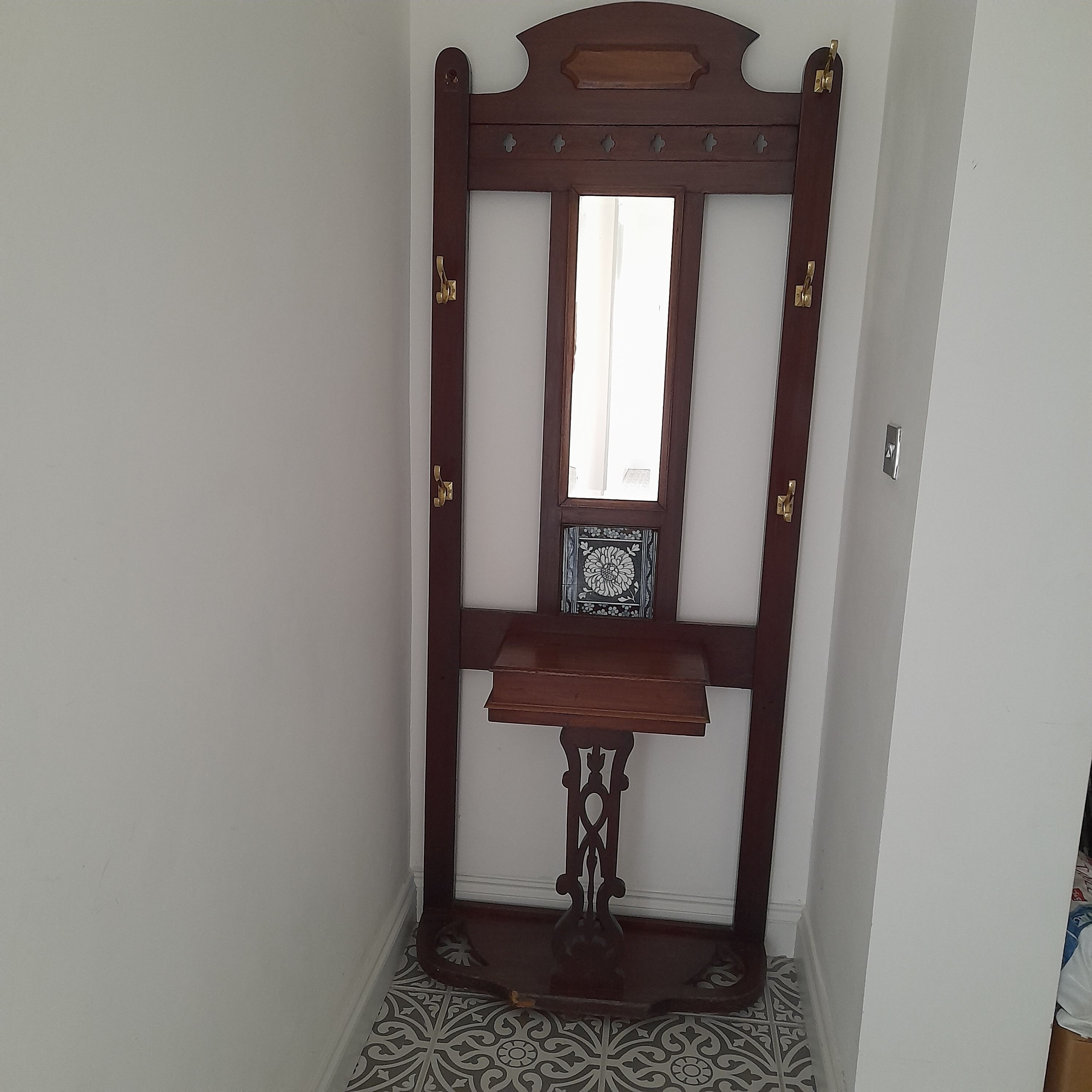 A wooden bench with a mirror and decorative elements in a hallway.