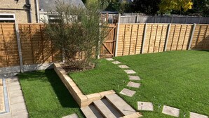 A well-maintained backyard with a stone pathway leading to a wooden gate, surrounded by a wooden fence and a grassy lawn. - Mill Villa: stunning 4 bed retreat 5 mins from Pakefield’s beautiful sandy beach (Lowestoft)