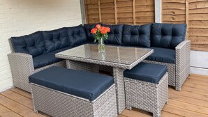 A corner seating area with a dark blue cushioned sofa, a glass-top table, and matching ottomans. - Mill Villa: stunning 4 bed retreat 5 mins from Pakefield’s beautiful sandy beach (Lowestoft)