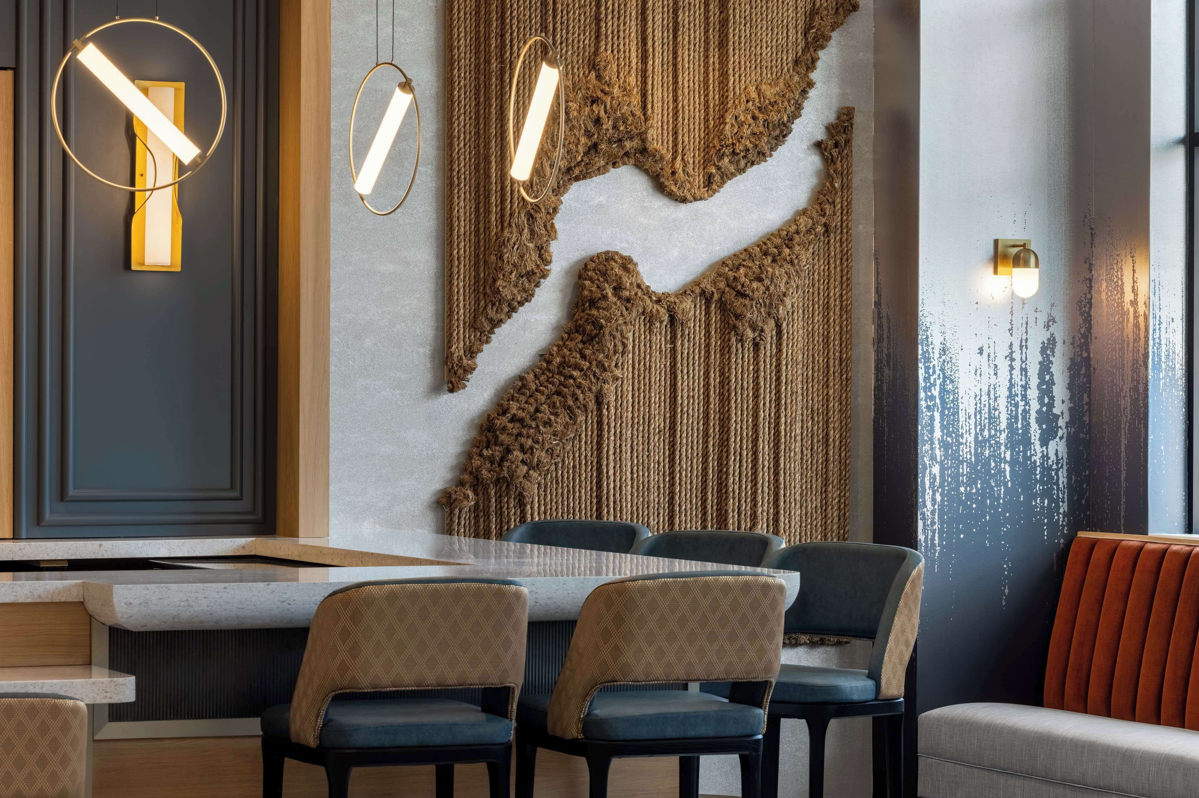 Un comedor moderno con una mesa larga, varias sillas y lámparas fijadas a la pared.