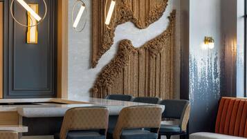 A modern dining area with a long table, multiple chairs, and wall-mounted lighting fixtures.