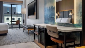 A modern hotel room with a large bed, a desk with a chair, a flat-screen TV, and a large window offering a city view. - Tempo By Hilton Louisville Downtown Nulu (Louisville)