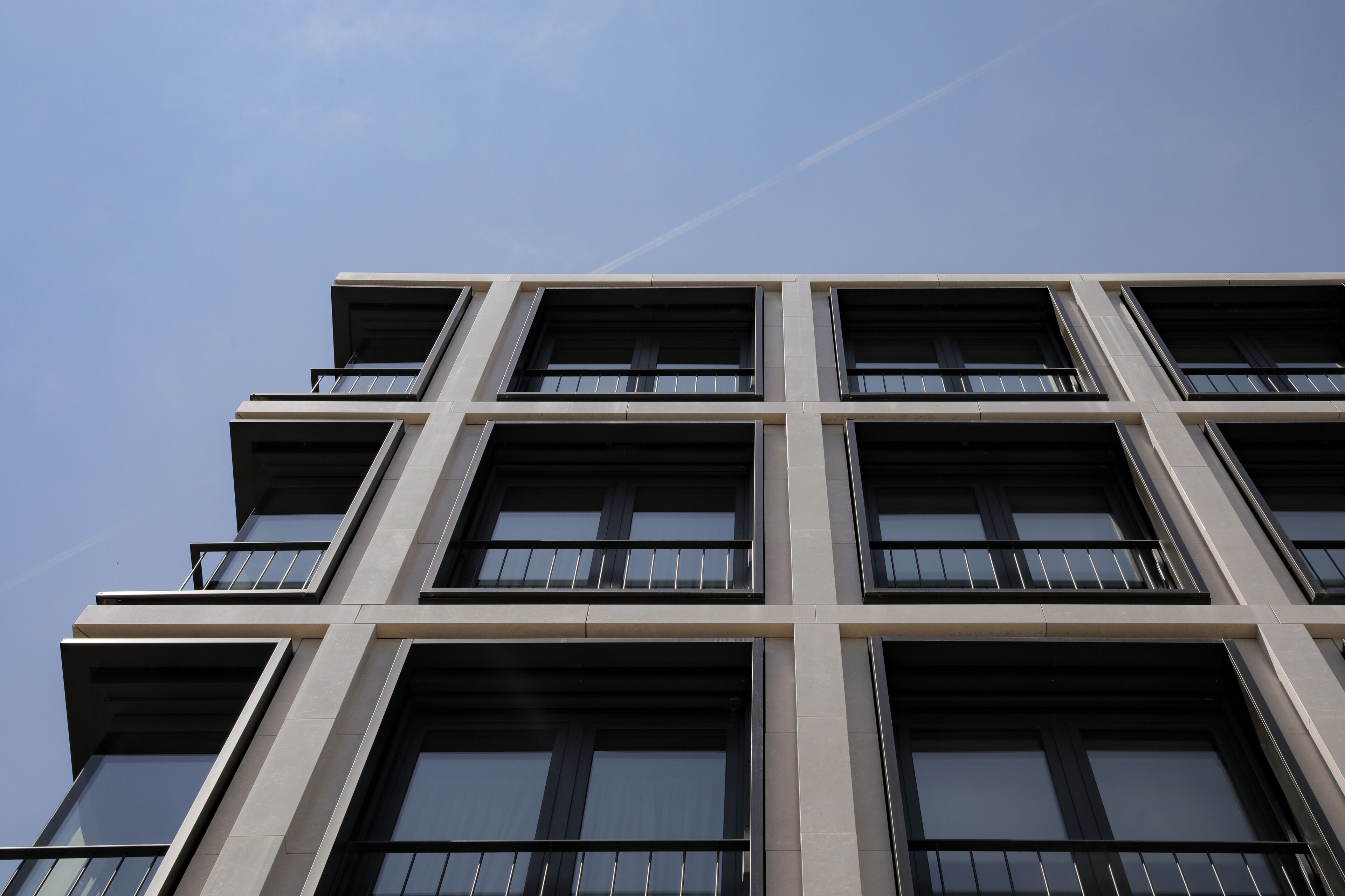 Un edificio de varios pisos con un diseño arquitectónico moderno, que cuenta con ventanas grandes y balcones.