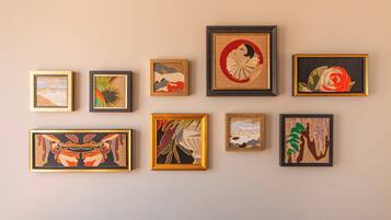 Eine Wand mit acht gerahmten Kunstwerken unterschiedlicher Stilrichtungen und Motive.