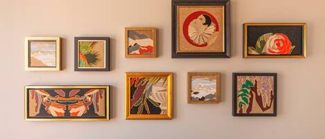 A wall with eight framed artworks of various styles and subjects.