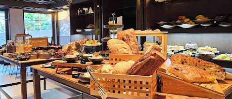 Un buffet proposant une variété de pains, de viennoiseries et de fruits.
