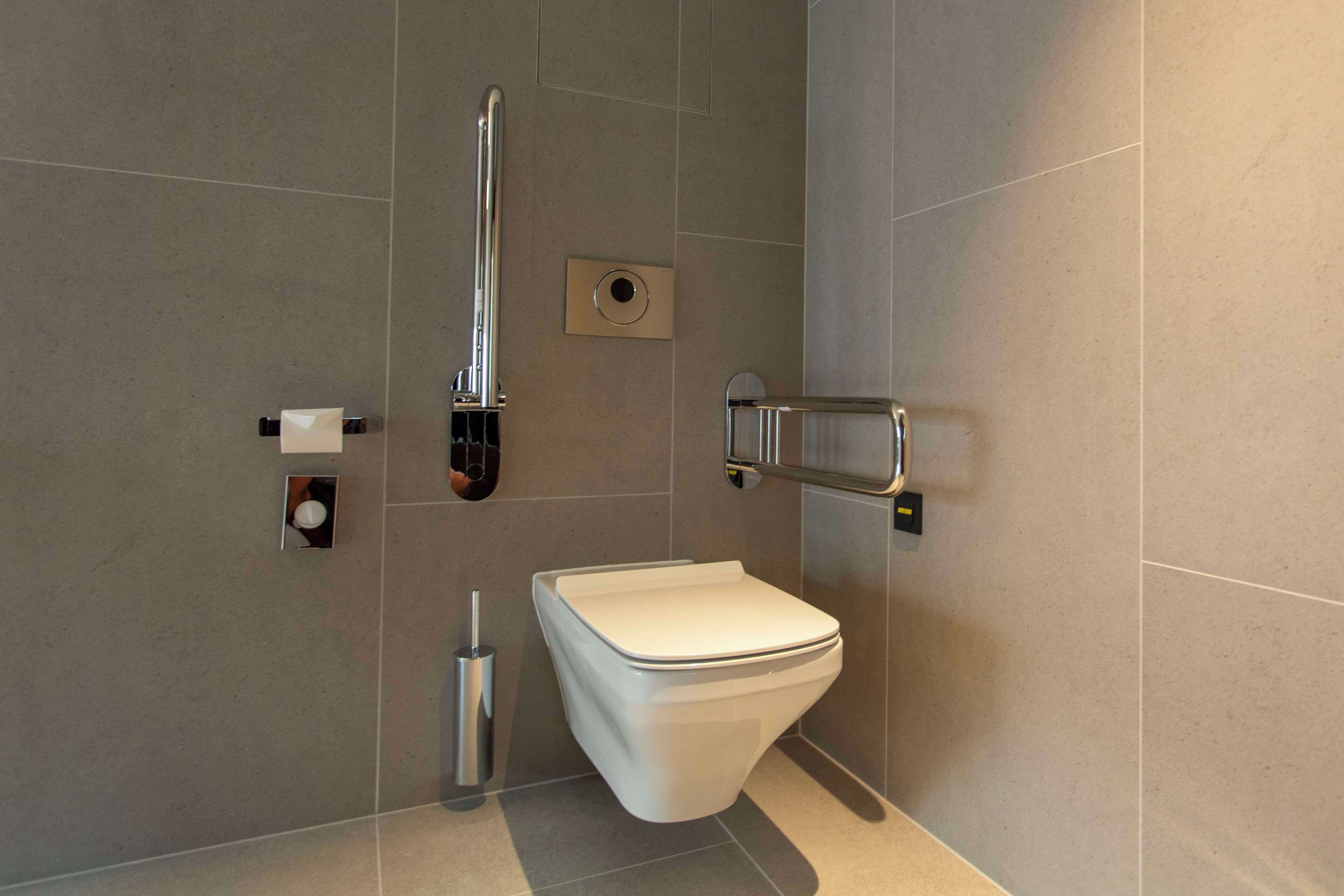 Een moderne badkamer met een wit toilet, een handdroger en een handgreep.