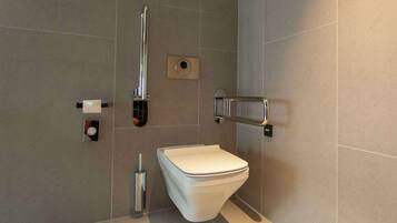 Een moderne badkamer met een wit toilet, een handdroger en een handgreep.