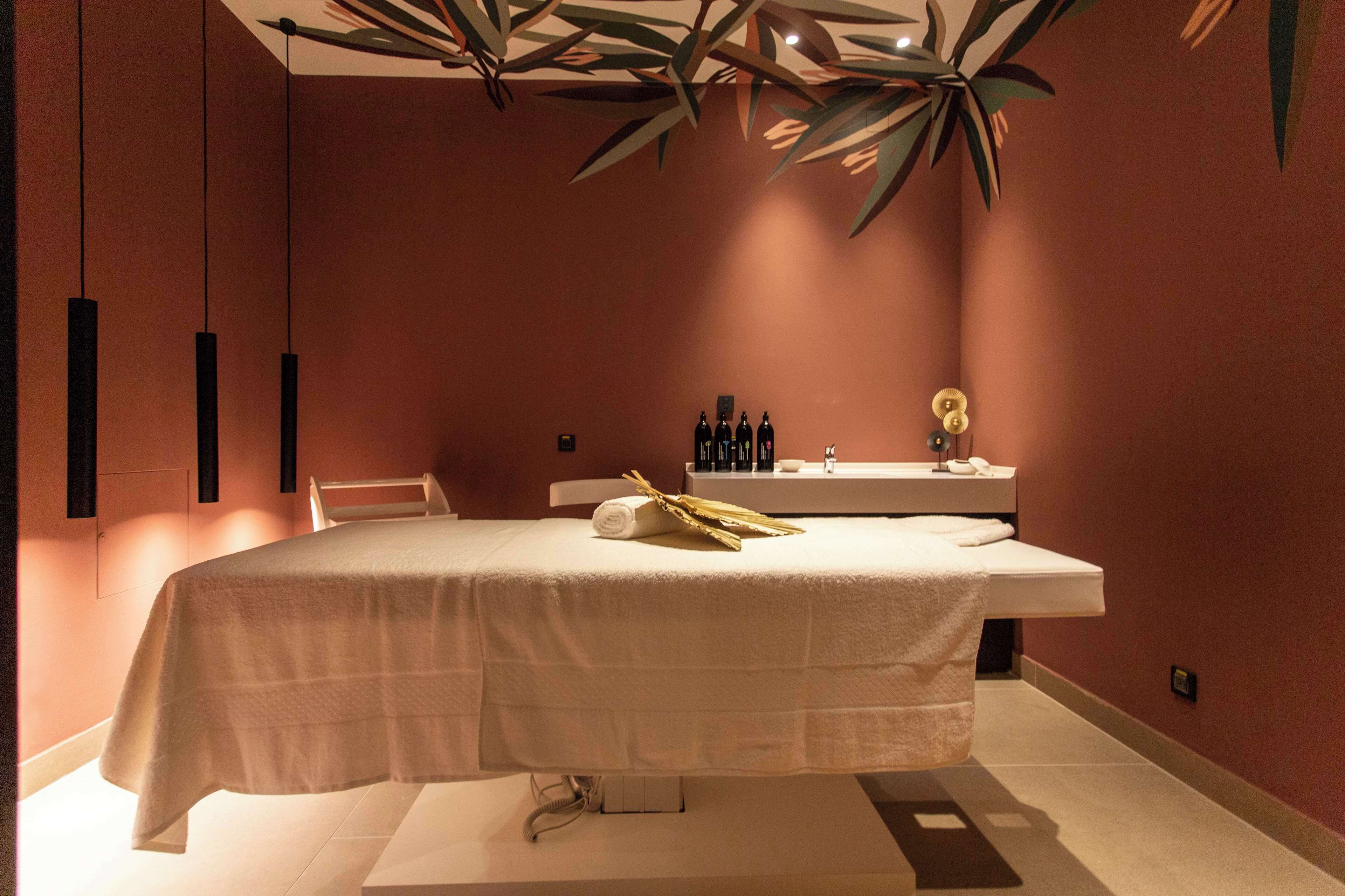 Une salle de spa équipée d’une table de massage, de serviettes et de bouteilles d’huiles.