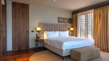 A modern hotel room with a large bed, bedside lamps, a wooden wardrobe, and a large window with curtains.
