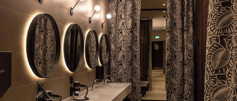 A modern bathroom with multiple mirrors, a vanity, and patterned curtains.