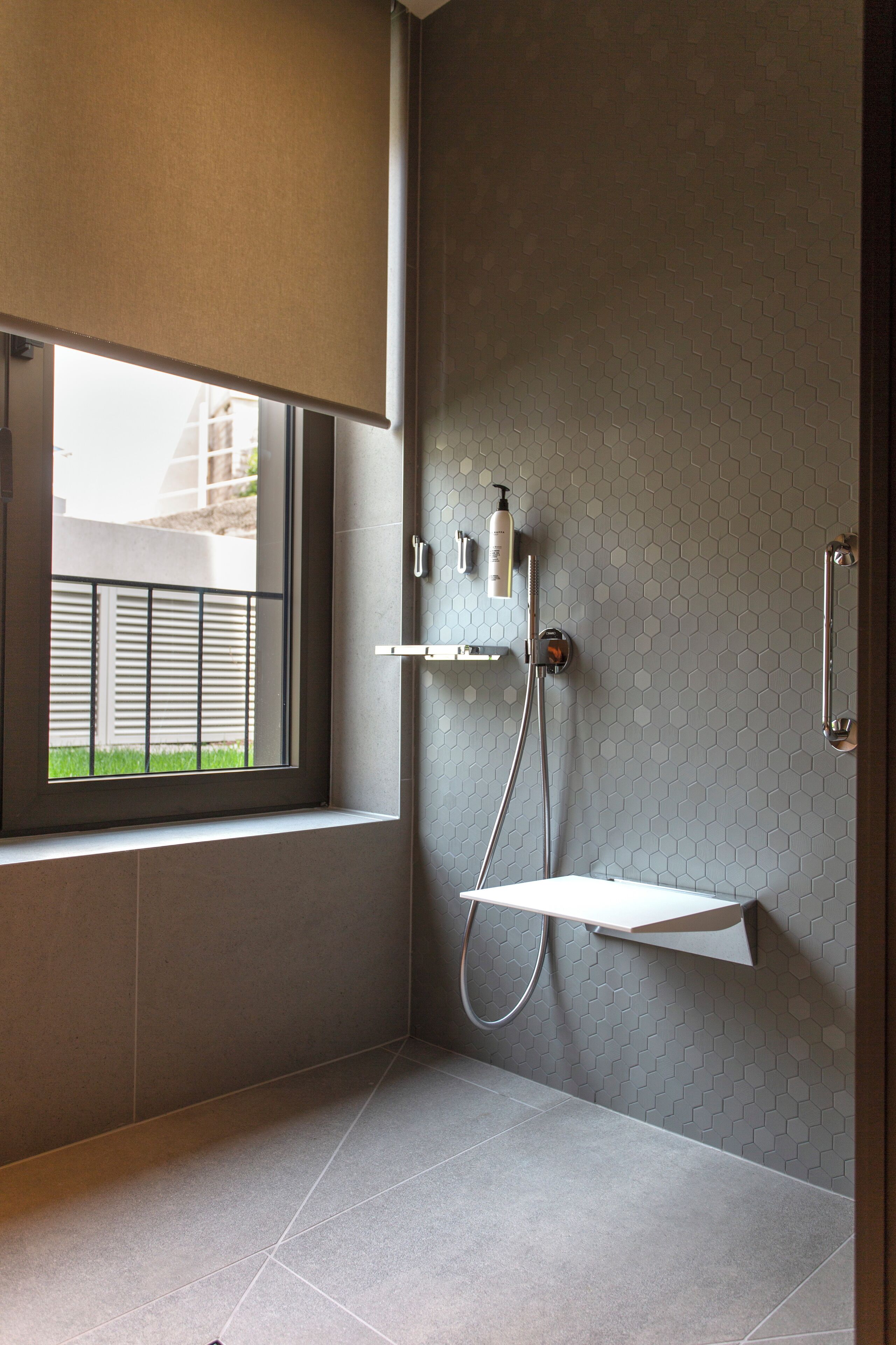 A modern bathroom with a shower, a window, and a towel rack.