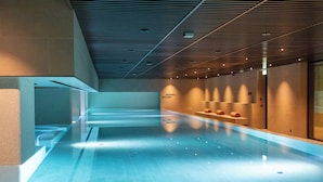 A modern indoor swimming pool with a clear water surface, a sloped ceiling with recessed lighting, and a wall with a no diving sign. - Keight Hotel Opatija, Curio Collection By Hilton (Opatija)