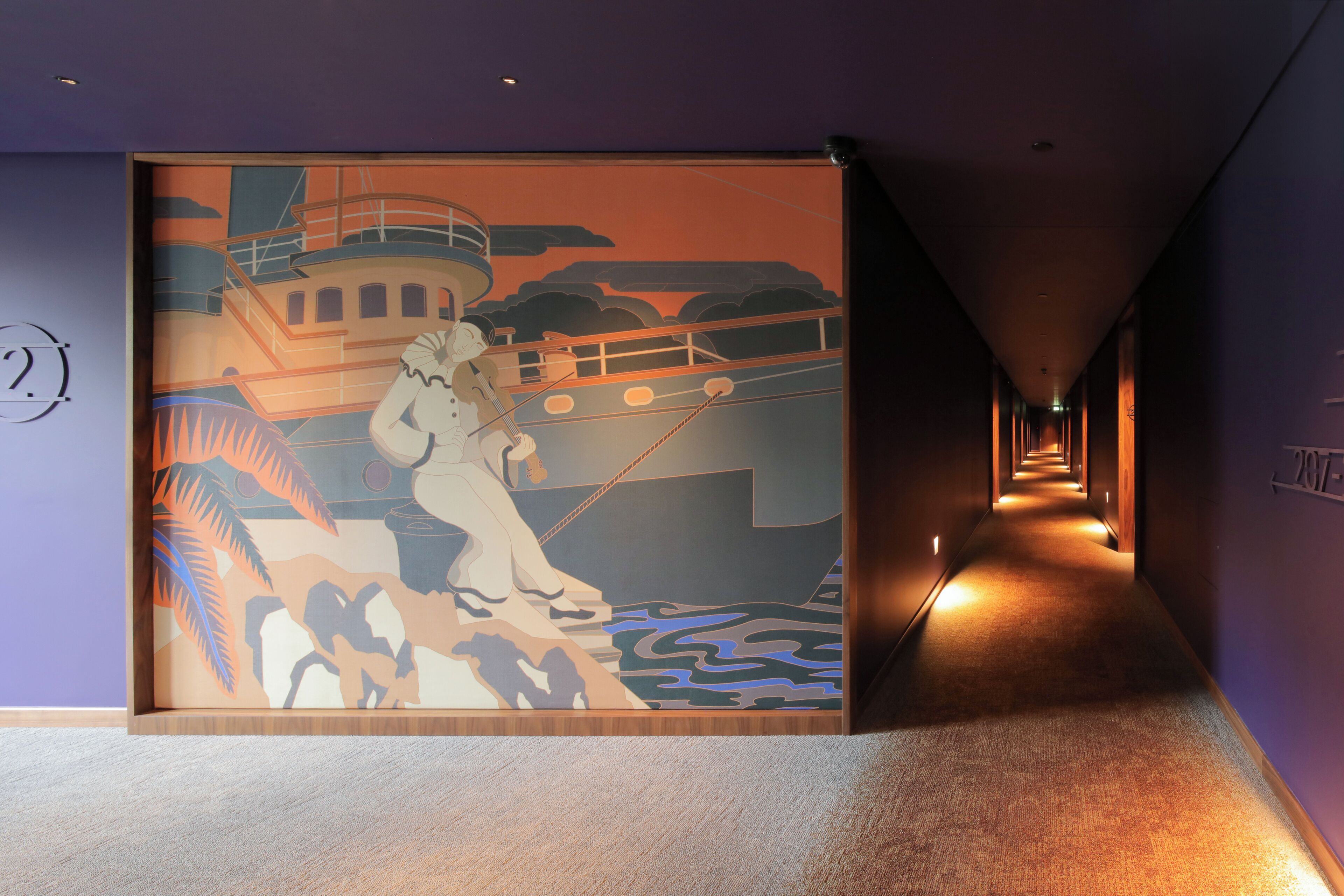A corridor with a mural of a ship and a woman, leading to a room with a wooden floor and a purple wall.