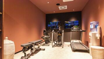 Une salle de sport équipée de tapis de course, de vélos elliptiques et de bancs de musculation.