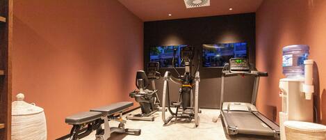 Ett gym med löpband, crosstrainers och träningsbänkar för styrketräning.