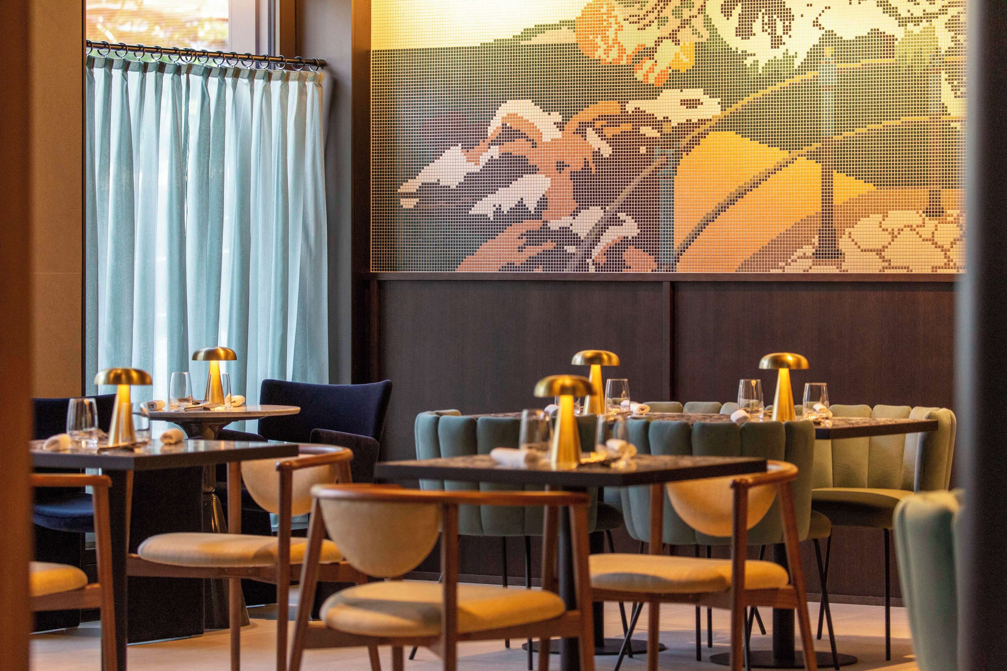 A restaurant with round tables, chairs, and pendant lighting.