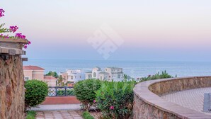Un sendero de piedra que conduce a un balcón con vistas a la costa, edificios y el mar.