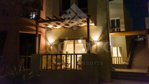 Un hotel con balcón, mobiliario exterior y una entrada bien iluminada.