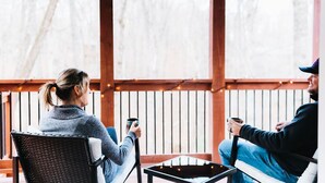 Two people sitting on a wooden deck with a table in between them, holding cups. - Modern Cabin, close to marina and downtown Blue Ridge (Blue Ridge)