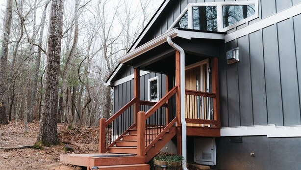 A modern house with a wooden staircase leading to a porch, surrounded by trees. - Modern Cabin, close to marina and downtown Blue Ridge (Blue Ridge)