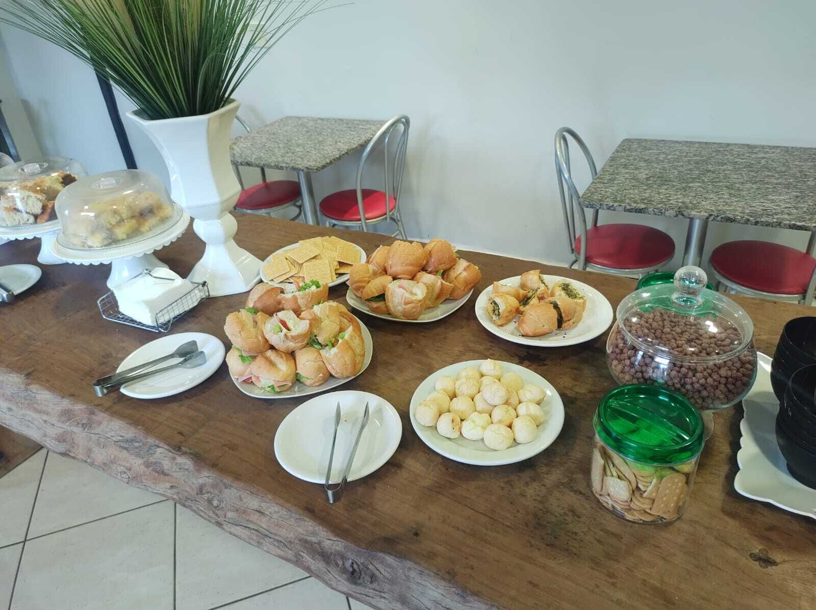 Una mesa de buffet con diversos alimentos, como sándwiches, pasteles y un tarro de galletas.