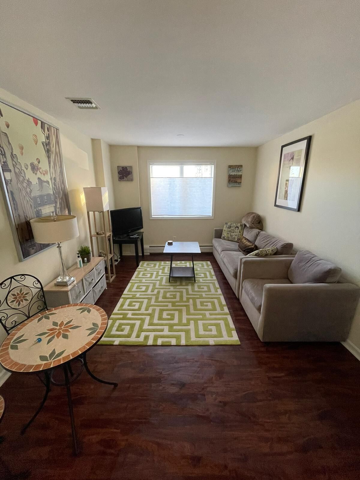 A living room with a sofa, a coffee table, a TV, and a patterned rug.
