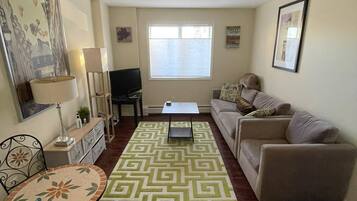 A living room with a sofa, a coffee table, a TV, and a patterned rug.