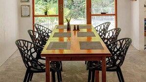 Un comedor con una mesa de madera, sillas negras y vistas amplias a través de grandes ventanales.