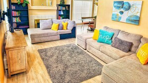 Una sala de estar con dos sofás, una mesa de centro, una estantería y un comedor con mesa y sillas.