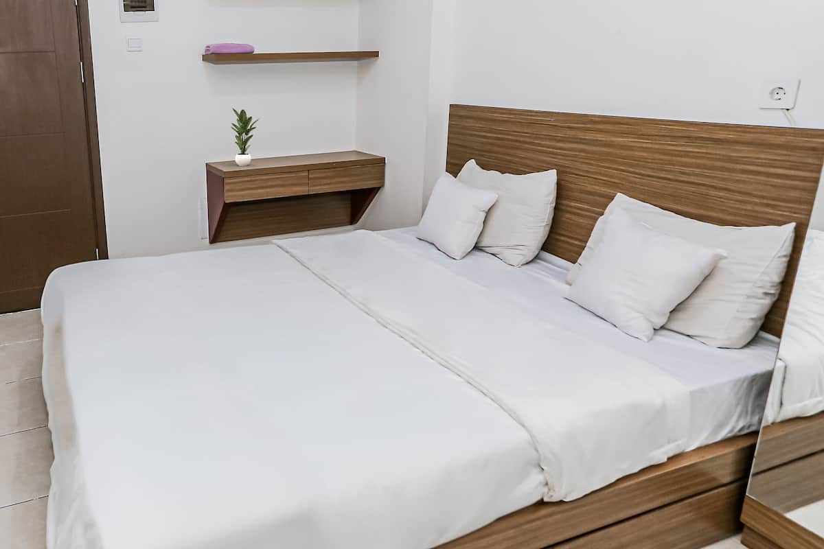 A neatly made bed with white linens and a wooden headboard.