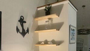 Ein modernes Zimmer mit Schreibtisch, Stuhl und Regalen mit Dekorationselementen.